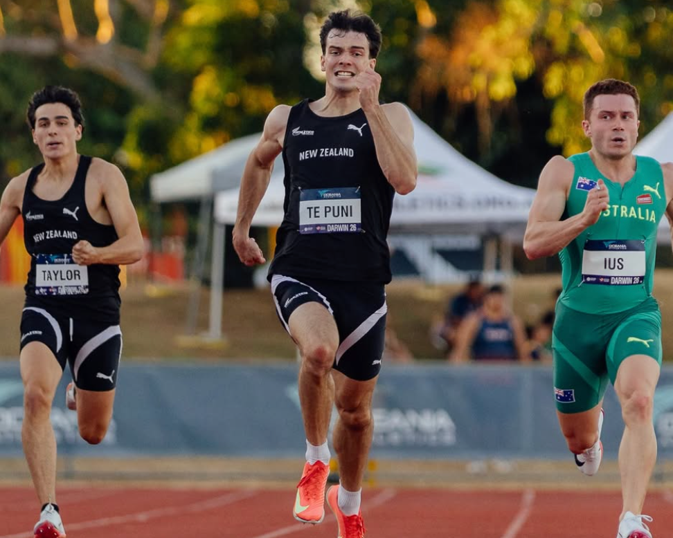 Three athletes running on a track with trees in the background